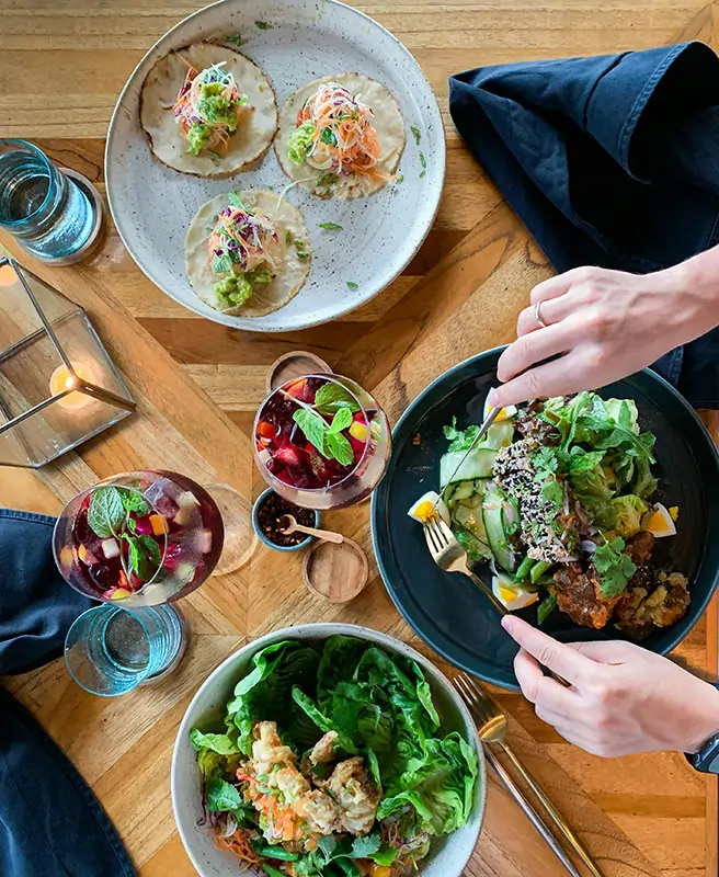 Overhead View of A Healthy Meal with Tacos, Salads, and Fruit Drinks on a Wooden Table